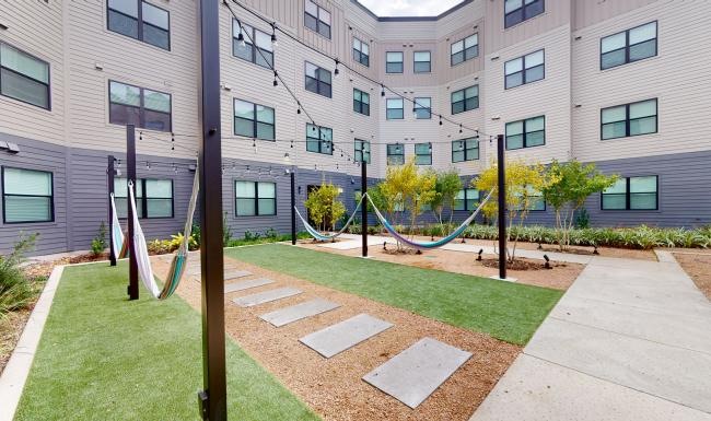 a building courtyard with a walkway and grass and hammocks