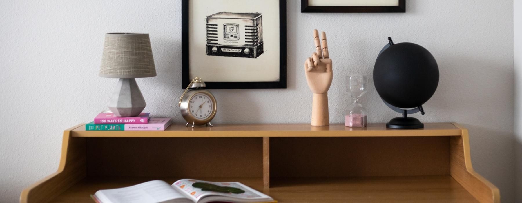 a desk with a clock and pictures on the wall
